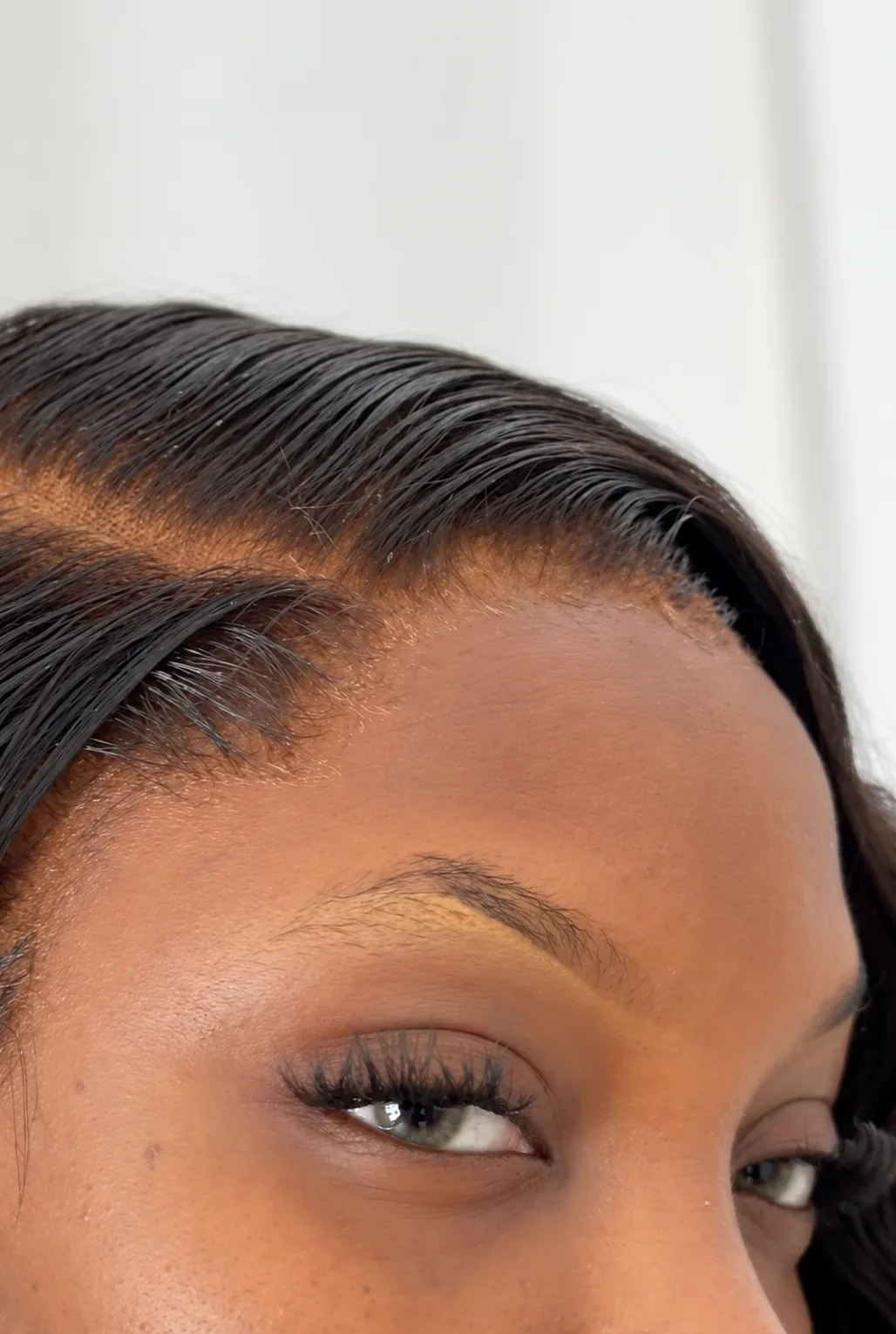 Close-up of a sleek side part and softly styled edges in black hair