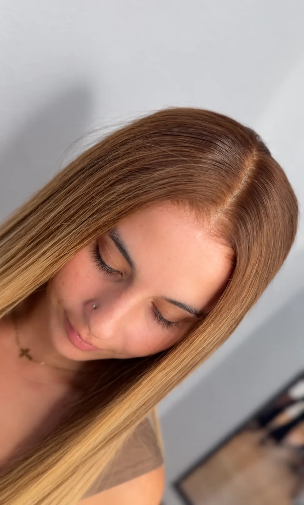 Close-up of a smooth side part in long caramel-blonde straight hair